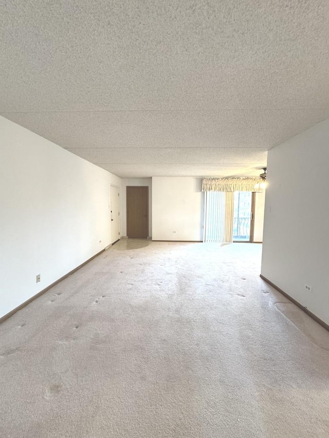 carpeted spare room with a textured ceiling and baseboards