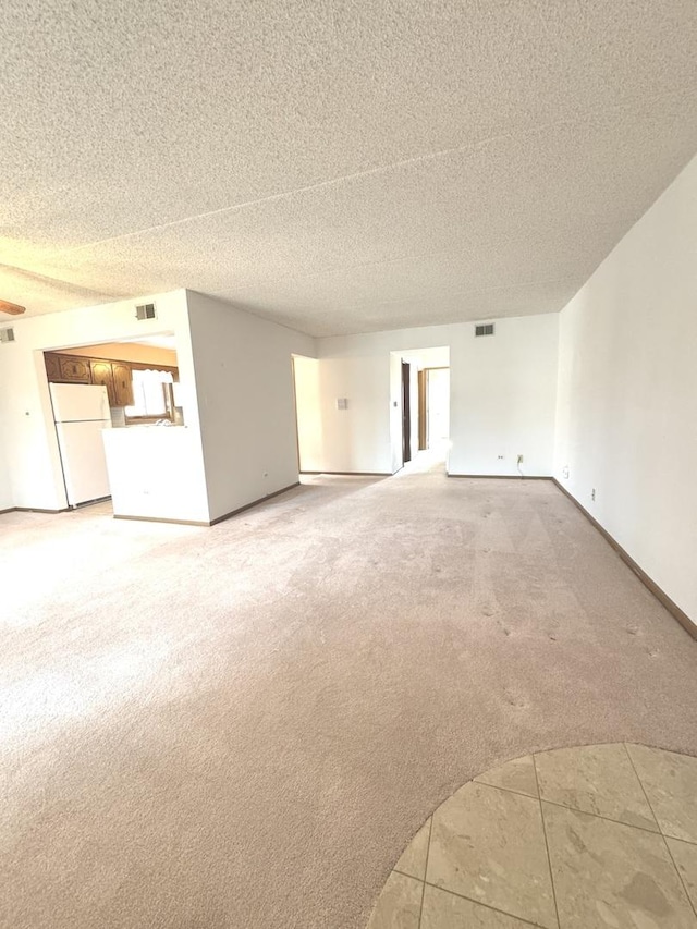 unfurnished living room featuring light carpet, baseboards, visible vents, and a textured ceiling