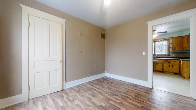 unfurnished dining area featuring light hardwood / wood-style floors, sink, and ceiling fan