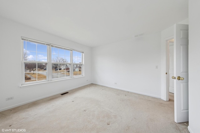 carpeted spare room with visible vents and baseboards