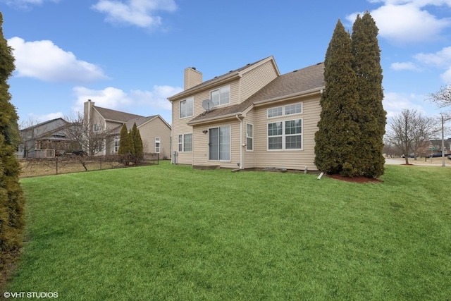 rear view of property featuring a yard and a chimney