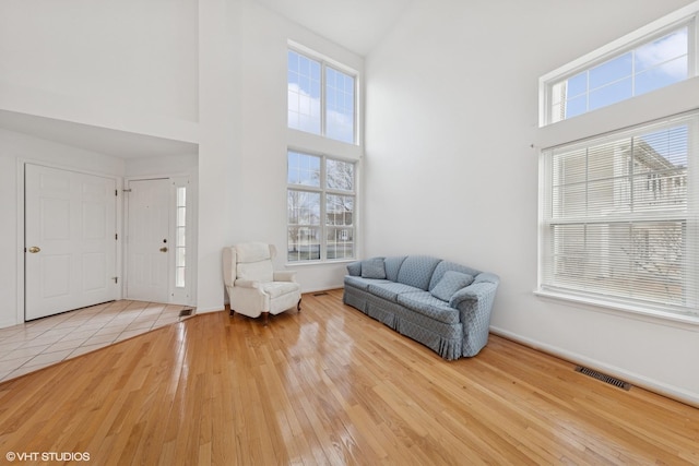 sitting room with visible vents, baseboards, a high ceiling, and wood finished floors