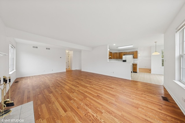 unfurnished living room featuring plenty of natural light, visible vents, and light wood-type flooring