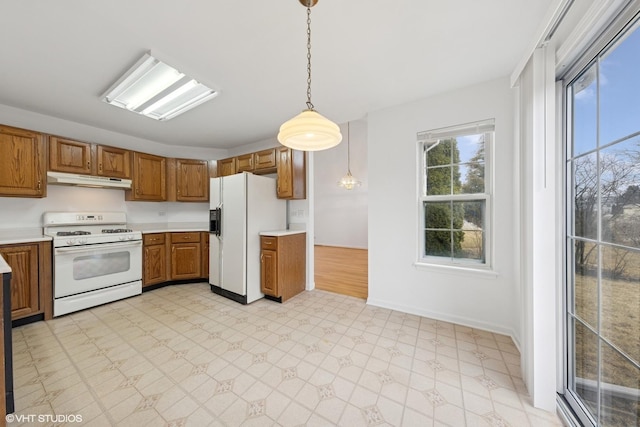 kitchen featuring brown cabinets, under cabinet range hood, white appliances, light countertops, and light floors