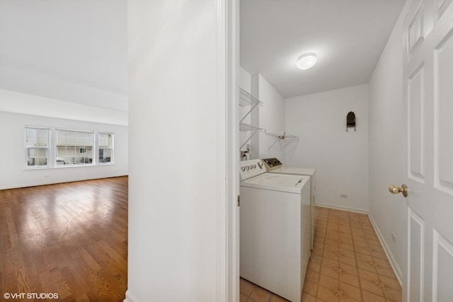 washroom featuring laundry area, baseboards, independent washer and dryer, and light wood-type flooring