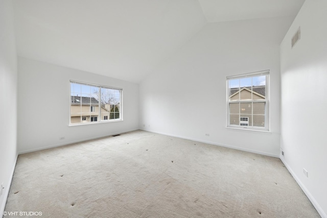 carpeted spare room with baseboards, visible vents, and high vaulted ceiling