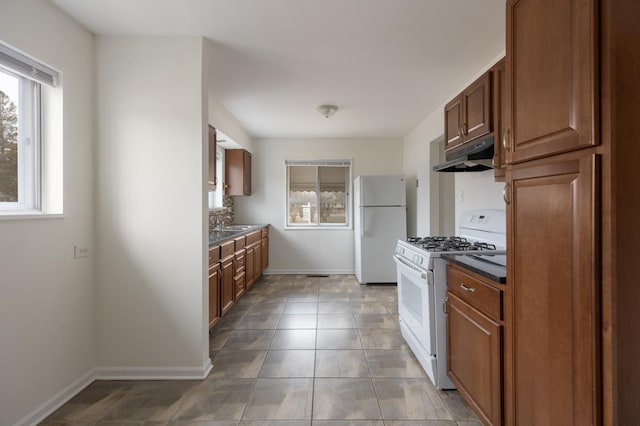 kitchen with tile patterned floors, a healthy amount of sunlight, backsplash, and white appliances