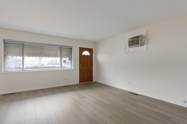 foyer entrance featuring a wall mounted AC and light hardwood / wood-style flooring