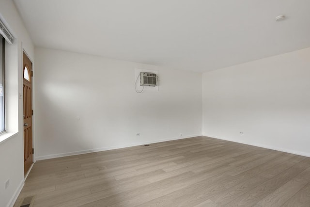 unfurnished room with light hardwood / wood-style floors and a wall unit AC