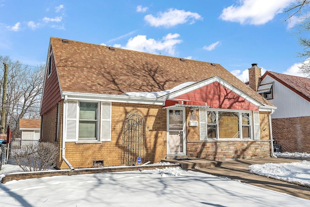 view of front of house featuring stone siding, a shingled roof, fence, and brick siding