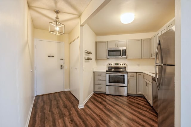 kitchen featuring stainless steel appliances, hanging light fixtures, gray cabinets, and dark hardwood / wood-style flooring