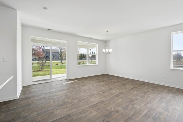 unfurnished dining area with dark hardwood / wood-style flooring, a notable chandelier, and a wealth of natural light