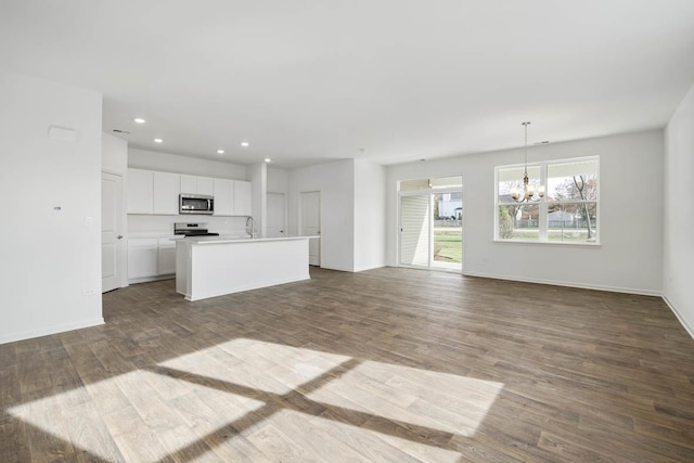 unfurnished living room featuring wood-type flooring, sink, and a notable chandelier