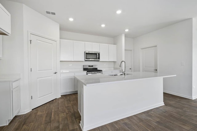 kitchen with stainless steel appliances, sink, a center island with sink, and white cabinets