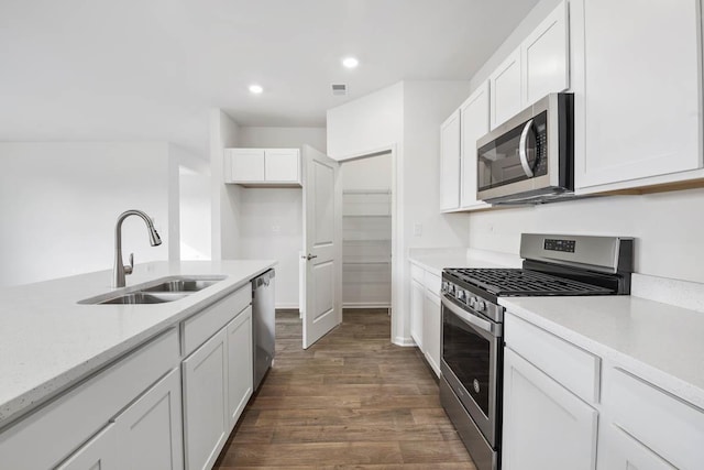 kitchen with stainless steel appliances, white cabinetry, sink, and dark wood-type flooring