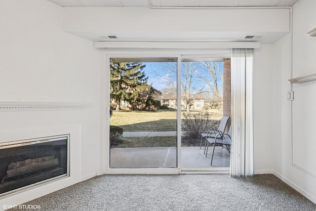 doorway to outside featuring visible vents, baseboards, a glass covered fireplace, and carpet floors