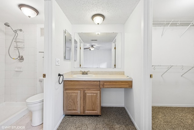 full bathroom with a walk in closet, toilet, a stall shower, a textured ceiling, and vanity