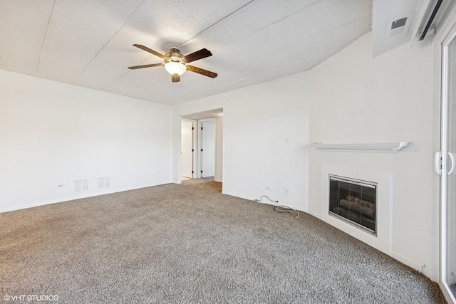 unfurnished living room with a glass covered fireplace, carpet flooring, visible vents, and ceiling fan