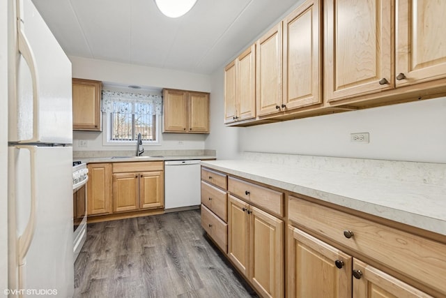 kitchen with white appliances, light brown cabinets, and a sink