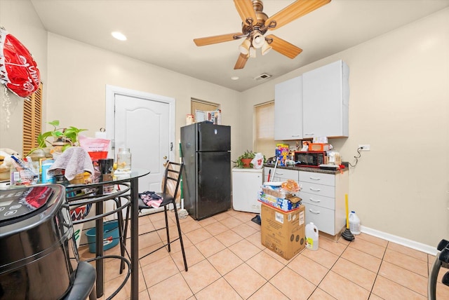 kitchen featuring white cabinets, light tile patterned floors, ceiling fan, and black refrigerator