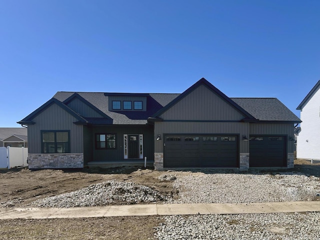 view of front of house with a garage, stone siding, and fence