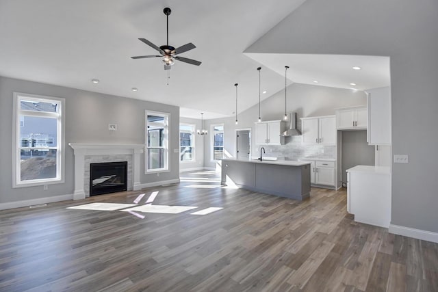 kitchen featuring a stone fireplace, white cabinetry, open floor plan, light countertops, and wall chimney exhaust hood