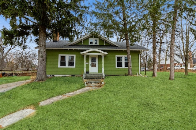 bungalow-style house featuring a shingled roof and a front yard