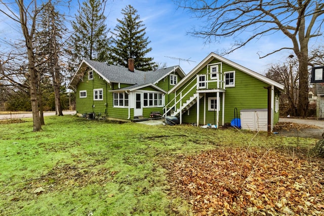 rear view of house featuring entry steps, a shingled roof, a lawn, a chimney, and cooling unit