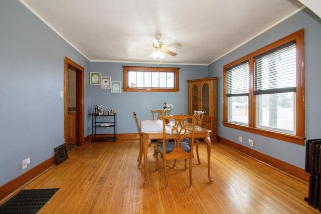 dining area with light wood-type flooring, baseboards, visible vents, and crown molding