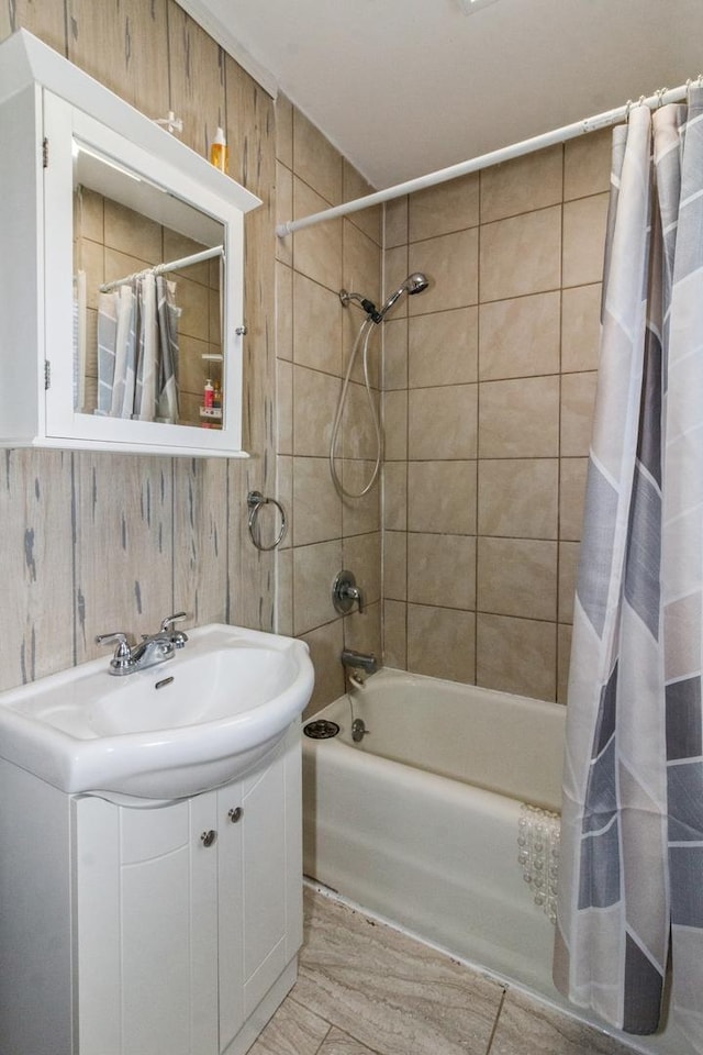 full bathroom with shower / bathtub combination with curtain, wooden walls, and vanity