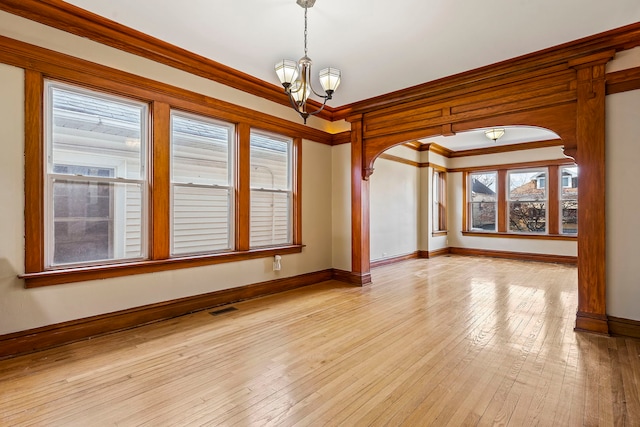 empty room featuring an inviting chandelier, crown molding, and light hardwood / wood-style flooring