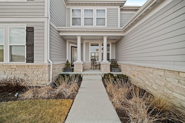 view of exterior entry featuring stone siding and a porch