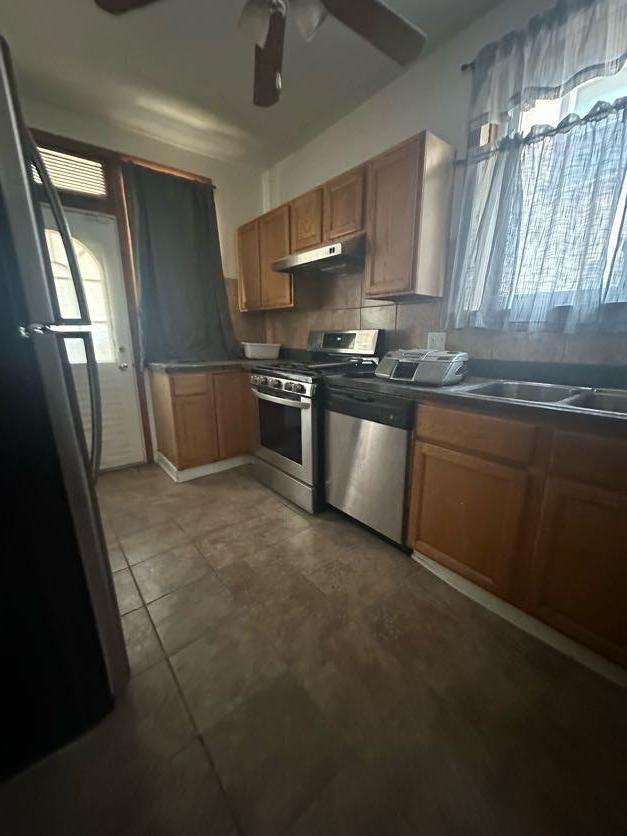 kitchen with appliances with stainless steel finishes, sink, ceiling fan, and decorative backsplash