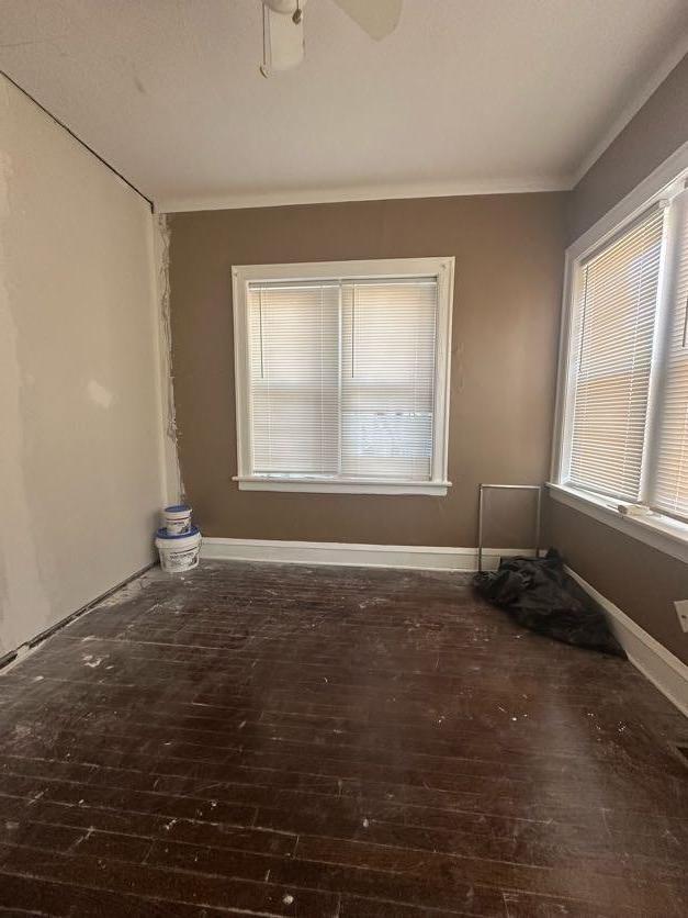 empty room with crown molding, dark hardwood / wood-style floors, and ceiling fan