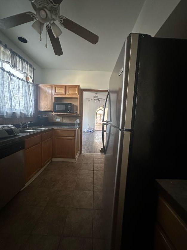 kitchen with appliances with stainless steel finishes, sink, dark tile patterned flooring, decorative backsplash, and ceiling fan