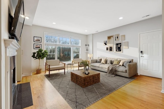 living room with a high end fireplace and hardwood / wood-style floors