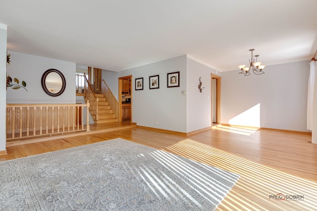 unfurnished room featuring a notable chandelier and light wood-type flooring