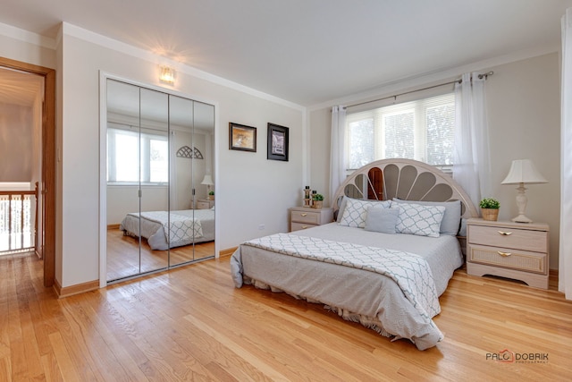 bedroom with crown molding, light wood-type flooring, and a closet