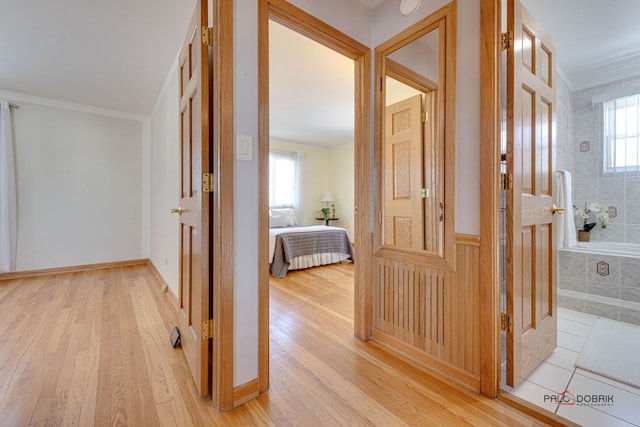 corridor with ornamental molding and light wood-type flooring