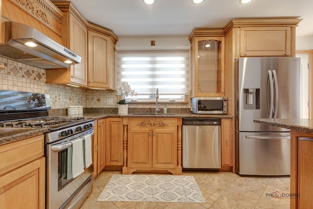 kitchen featuring sink, light tile patterned floors, appliances with stainless steel finishes, dark stone countertops, and backsplash