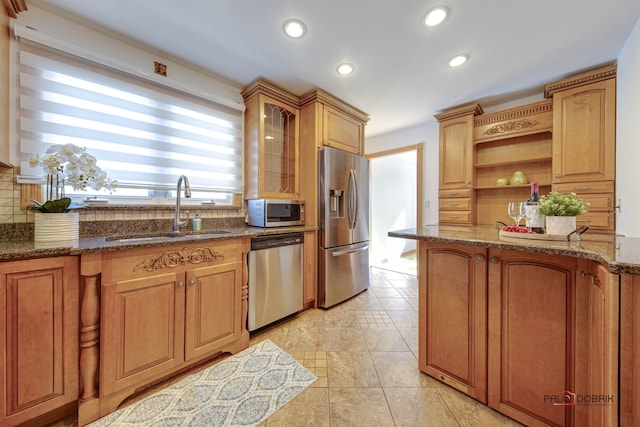 kitchen with sink, decorative backsplash, stainless steel appliances, and dark stone counters