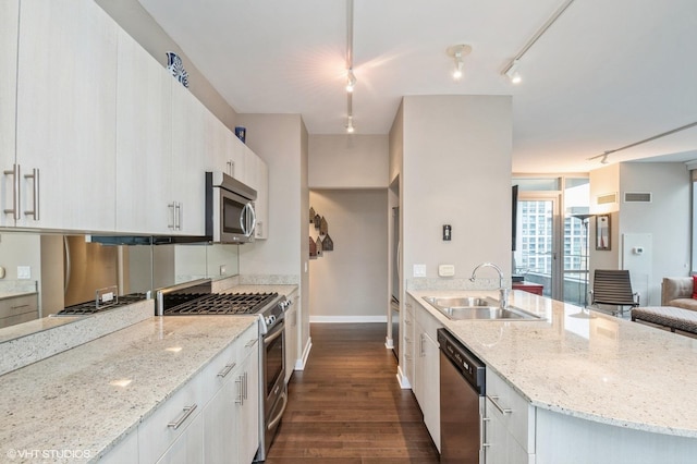 kitchen with sink, light stone counters, white cabinetry, stainless steel appliances, and dark hardwood / wood-style flooring