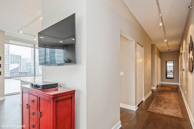corridor with rail lighting and dark hardwood / wood-style floors