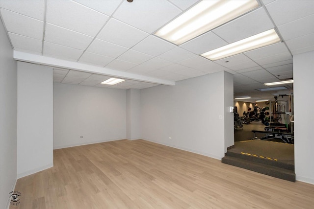 finished basement with a drop ceiling, wood finished floors, and baseboards