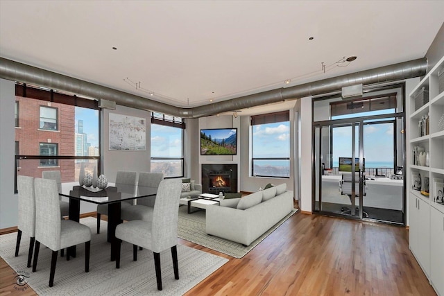 dining space with a wealth of natural light, a warm lit fireplace, and wood finished floors