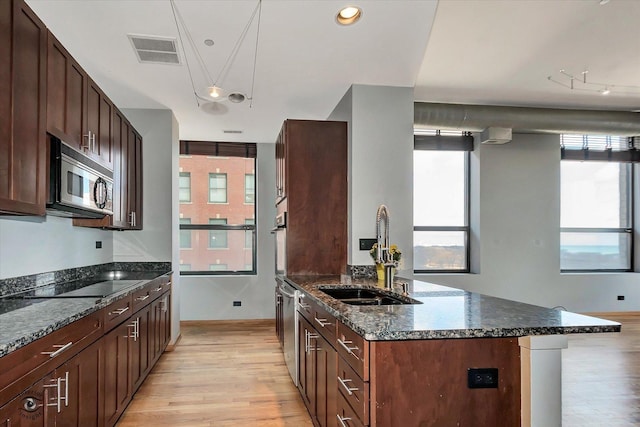 kitchen featuring light wood finished floors, visible vents, dark stone counters, appliances with stainless steel finishes, and a sink