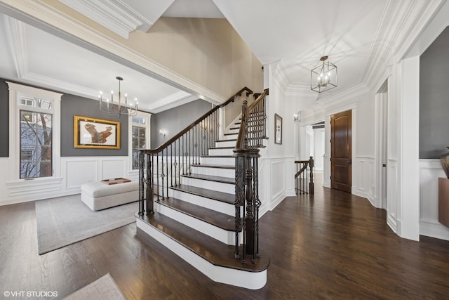 entrance foyer featuring plenty of natural light, dark hardwood / wood-style flooring, a notable chandelier, and ornamental molding