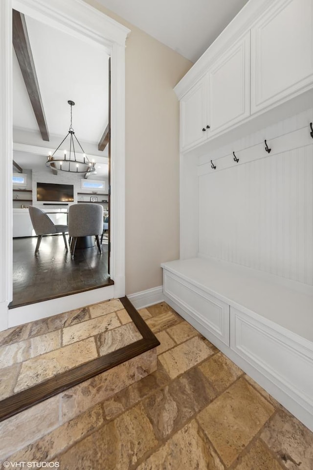 mudroom featuring a notable chandelier and beam ceiling