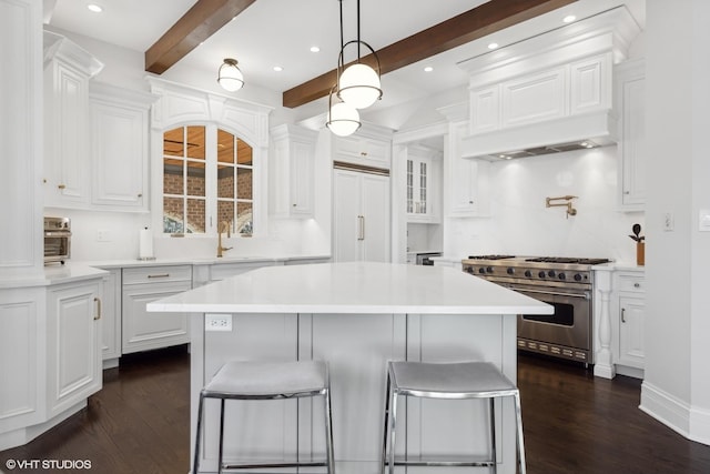 kitchen with white cabinets, high end appliances, beamed ceiling, and a center island