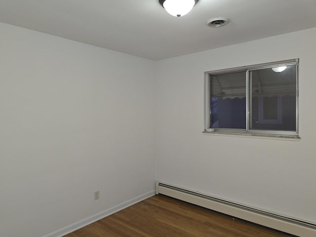 unfurnished room featuring a baseboard heating unit and dark wood-type flooring